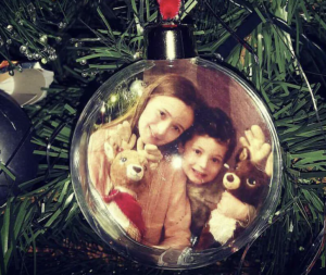 Pic of two children in a photo bauble hanging from a Christmas tree as a decoration